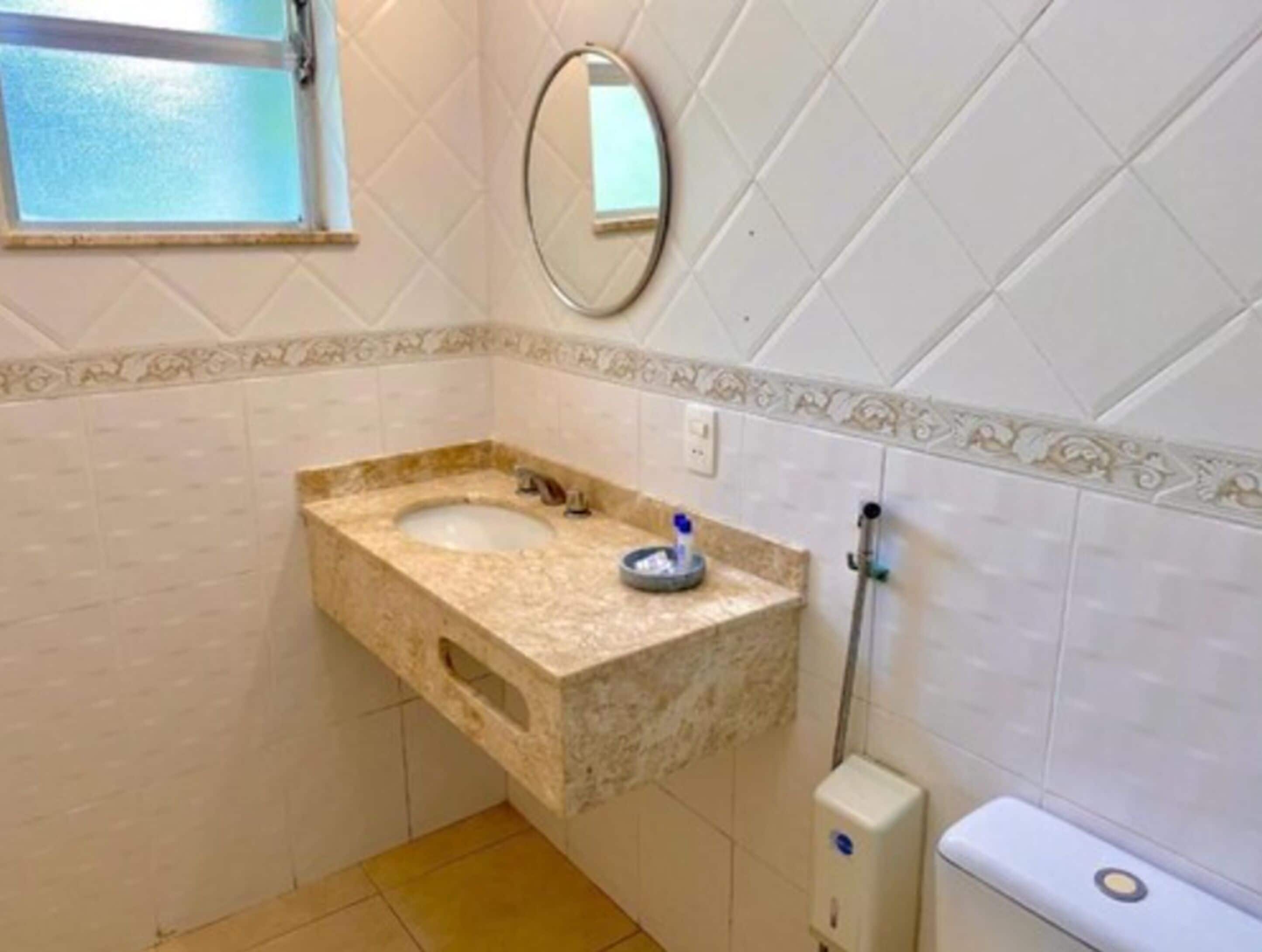 A bathroom with a marble sink, a mirror, and a toilet.