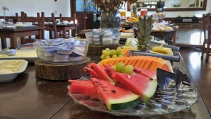 A buffet table with various food items including watermelon, grapes, and other fruits. - Hotel Vila Bavaria (Petrópolis)