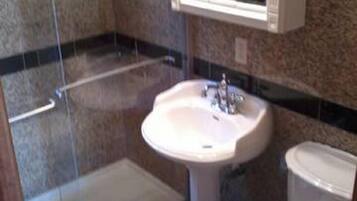 A bathroom with a shower, sink, and toilet.