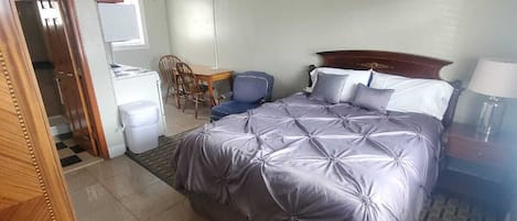 A bedroom with a bed, a ceiling fan, a desk, and a chair.