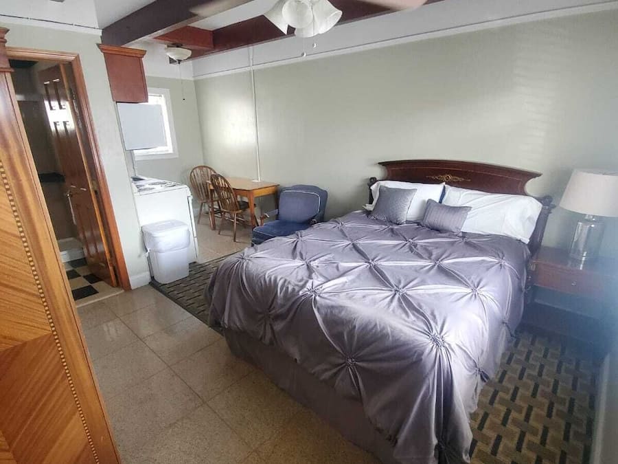 Quarto com uma cama, um ventilador de teto, escrivaninha e uma cadeira.