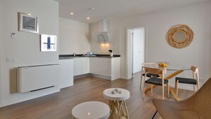 A modern kitchen with white cabinets, a built-in oven, and a dining area with a glass table and chairs.