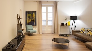 A modern living room with a sofa, a coffee table, a TV stand, and a painting on the wall.