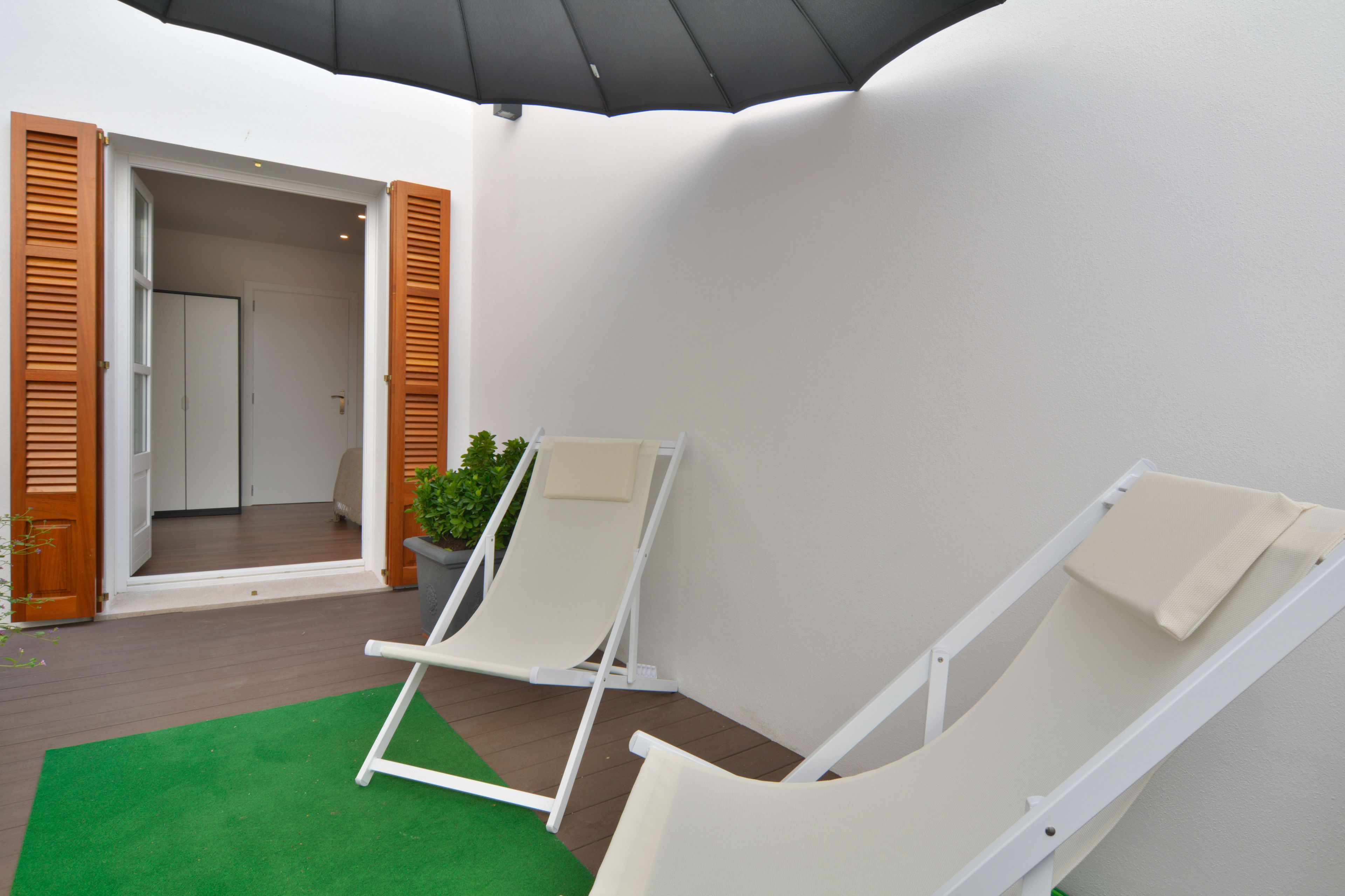Quarto com duas poltronas reclináveis, uma planta em vaso e uma porta que dá para outro cômodo.
