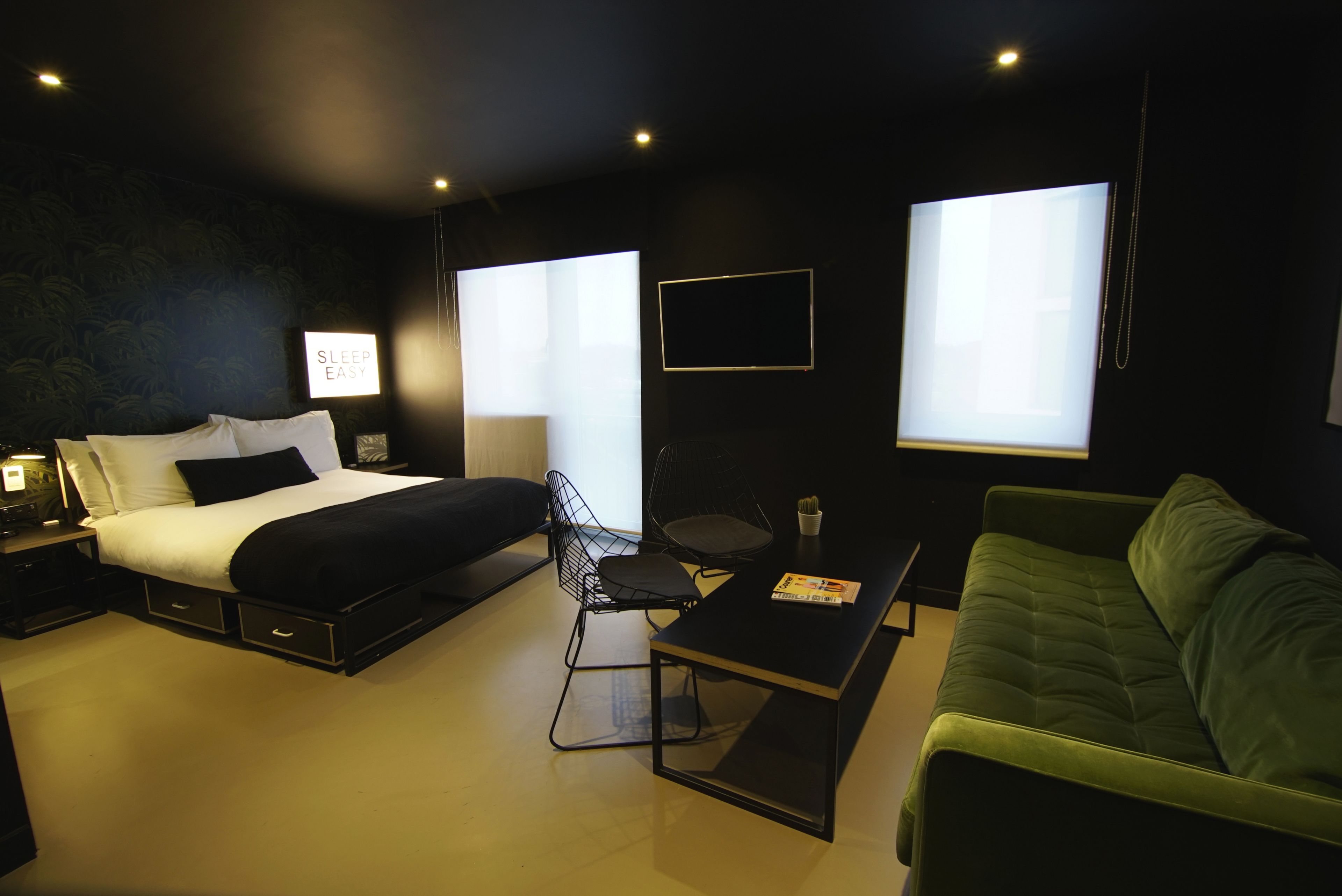 Una camera da letto moderna con un letto, un divano verde, un tavolino e una sedia.