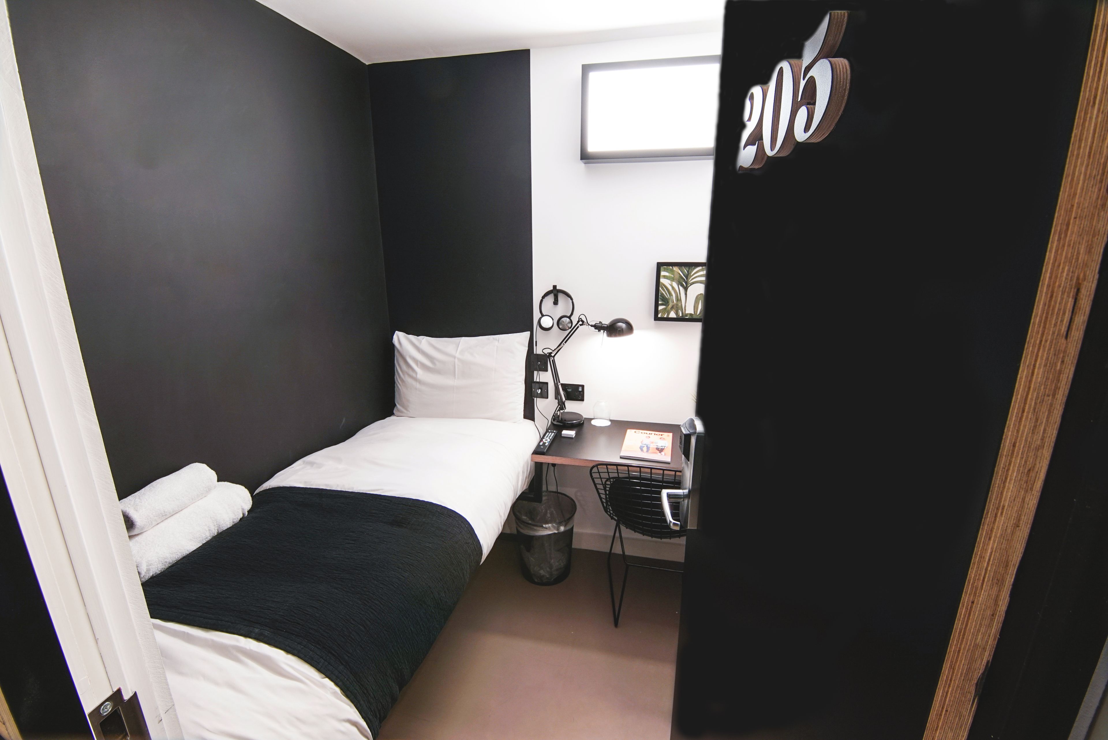 Una habitación de hotel pequeña con una cama individual, un escritorio y una silla.