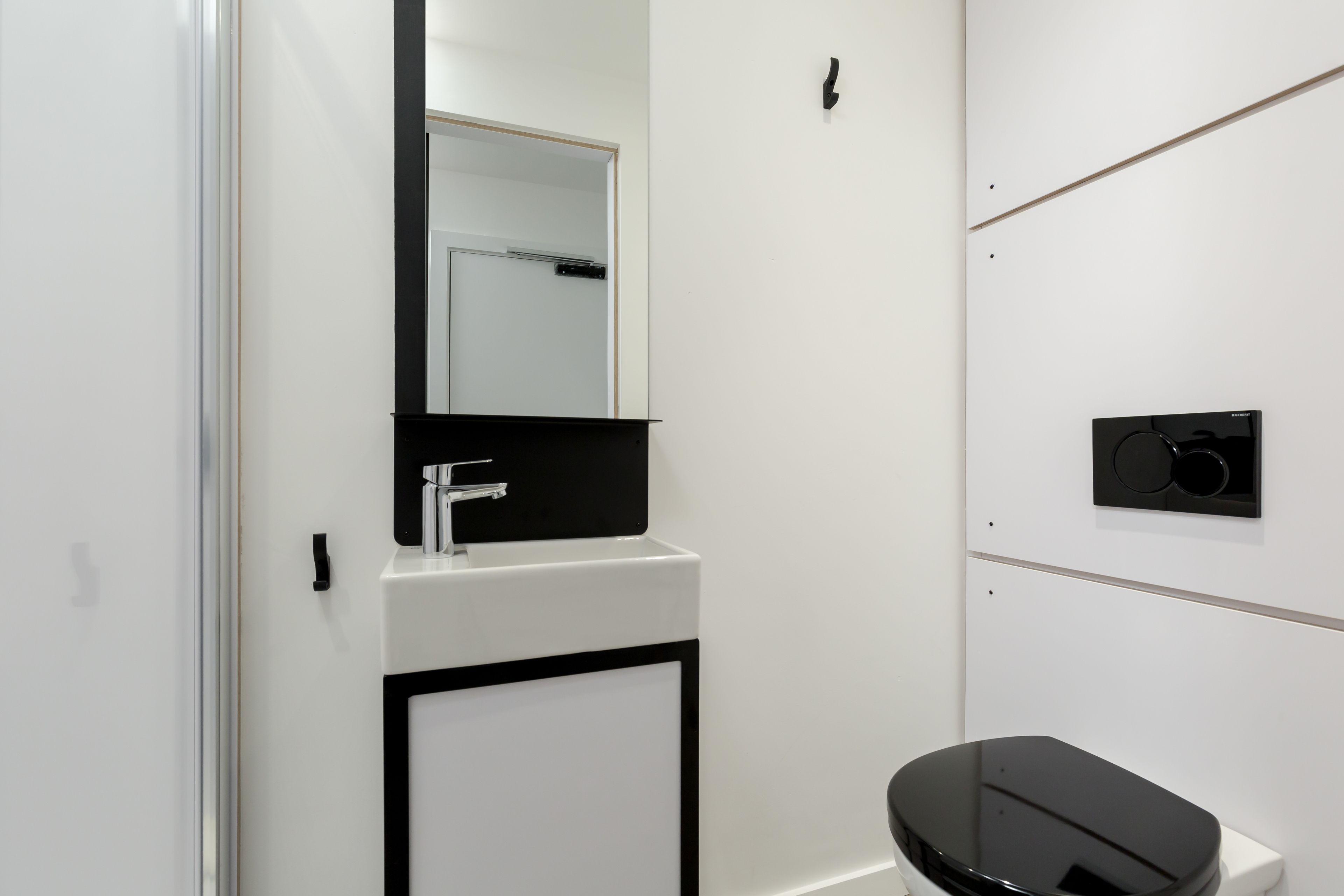 Casa de banho moderna com lavatório branco, torneira preta e sanita preta.