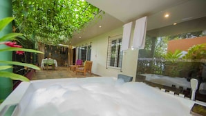 Un área de spa con hidromasaje, sillas de madera y una mesa.