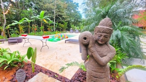 Un jardín con una estatua, una piscina y mobiliario para exteriores.