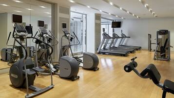 Un gimnasio con diversos equipos de ejercicio, incluyendo cintas de correr y elípticas.
