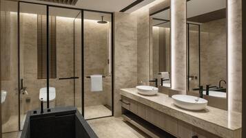 A modern bathroom with a large mirror, two sinks, a bathtub, and a toilet.