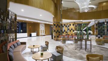 A spacious lobby with a modern design, featuring a reception desk, seating areas, and a decorative wall with geometric patterns.