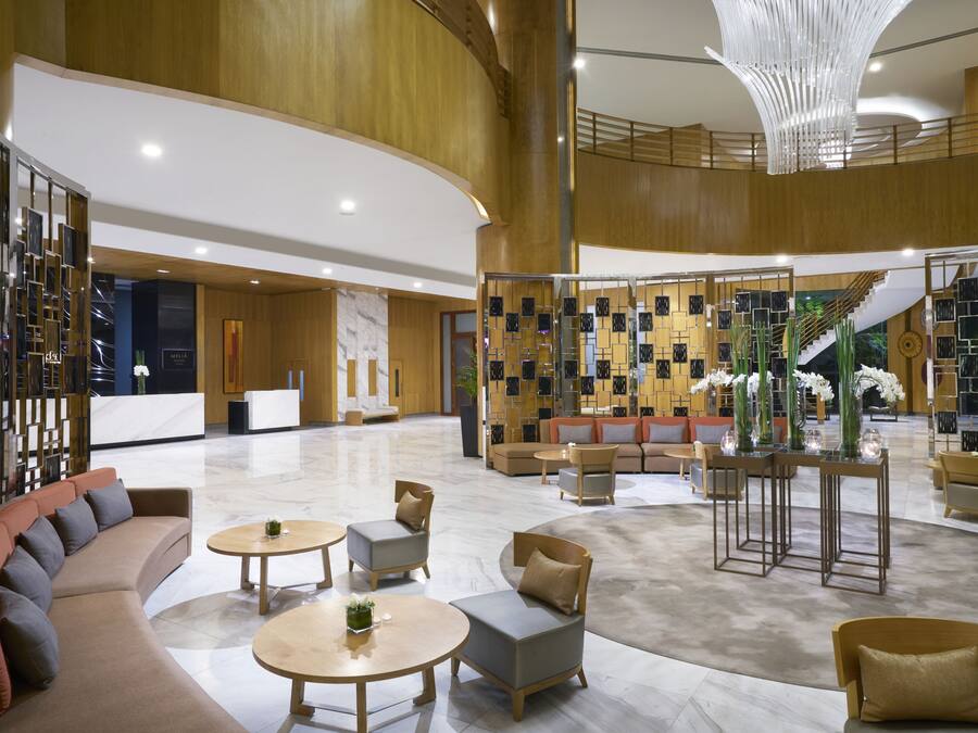 A spacious lobby with a modern design, featuring a reception desk, seating areas, and a decorative wall with geometric patterns.