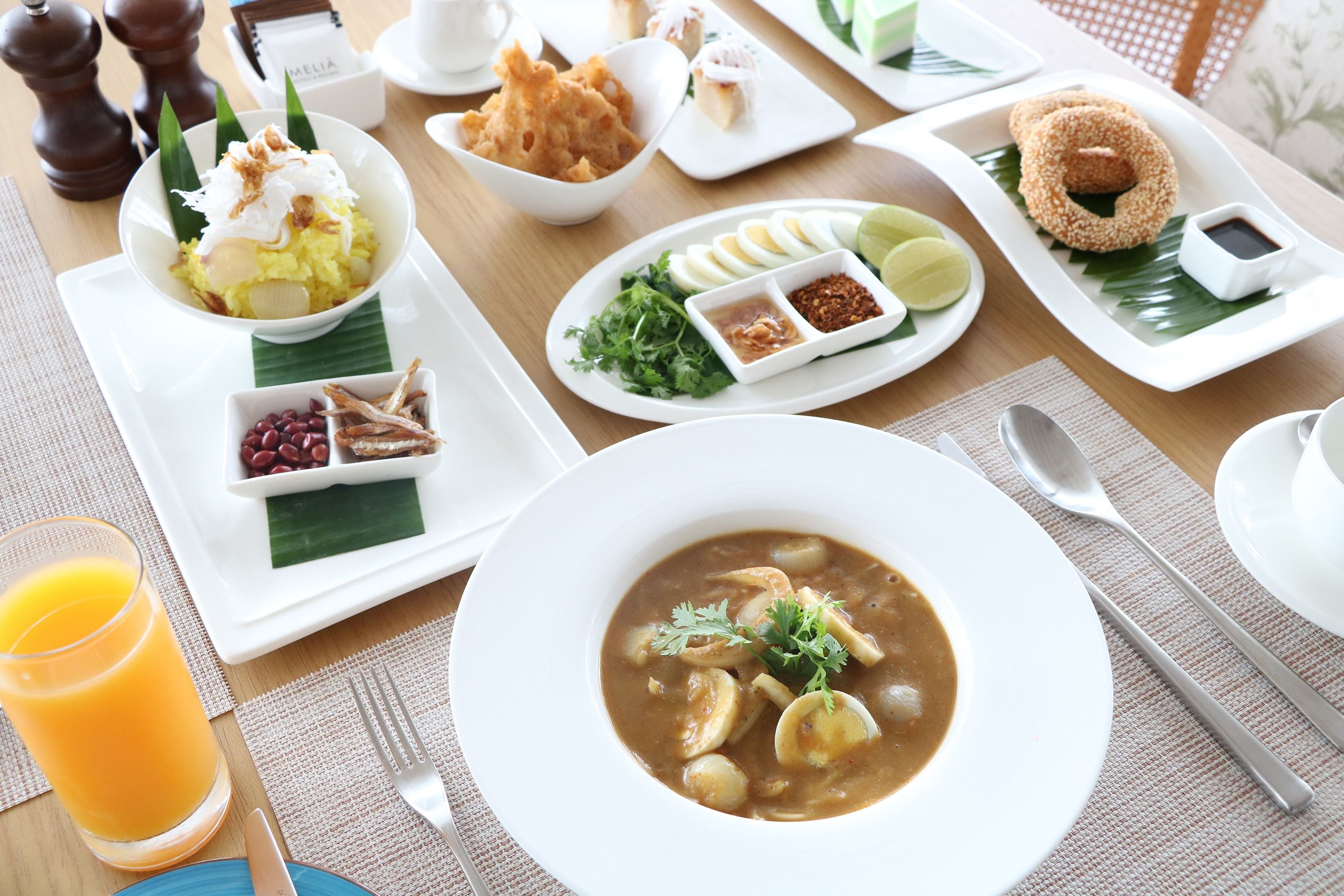 A breakfast setting with various dishes including soup, eggs, and a bowl of rice.