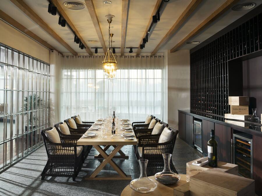 A dining area with a long table set for six, surrounded by wicker chairs.