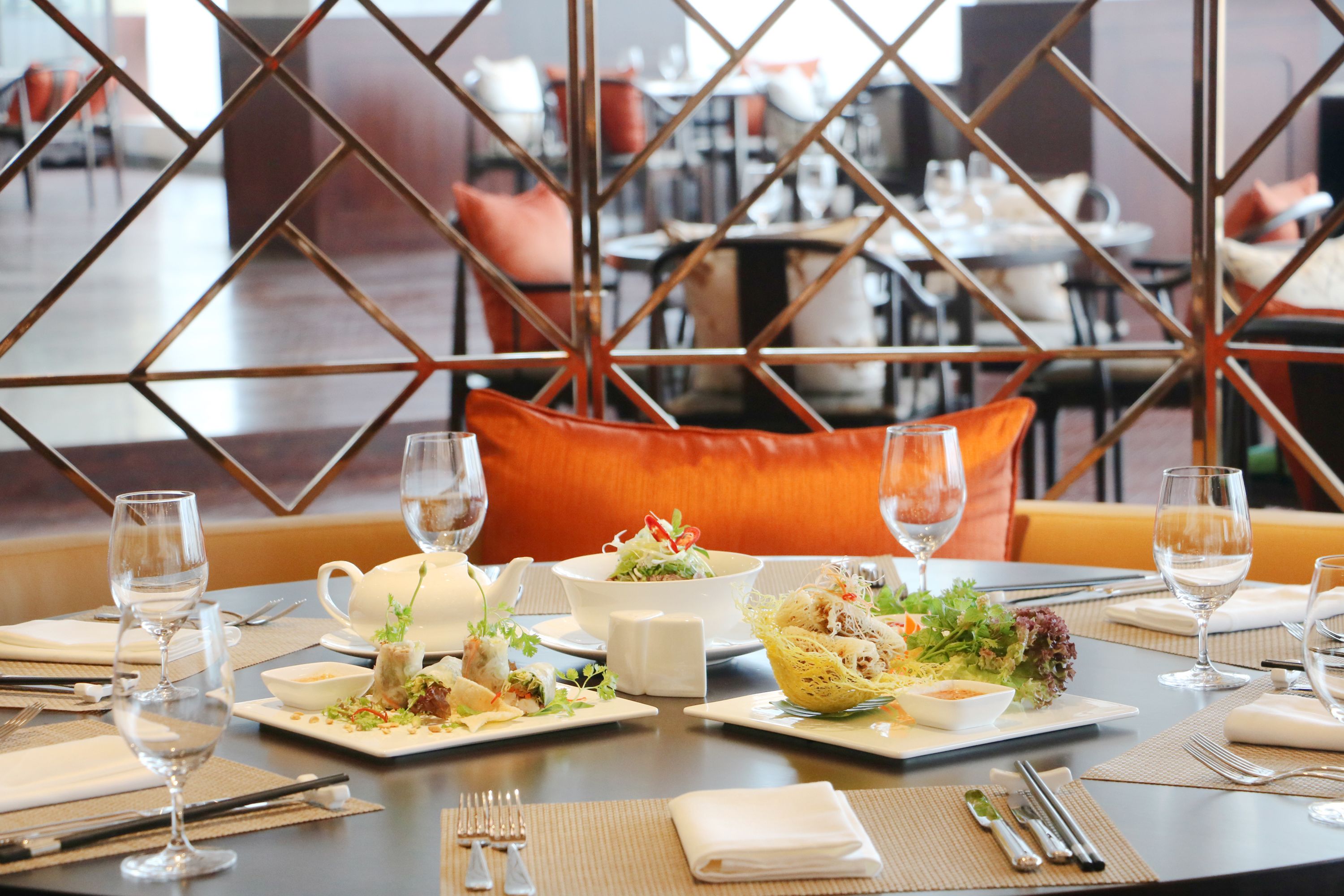 A dining table set with plates of food, glasses, and cutlery.