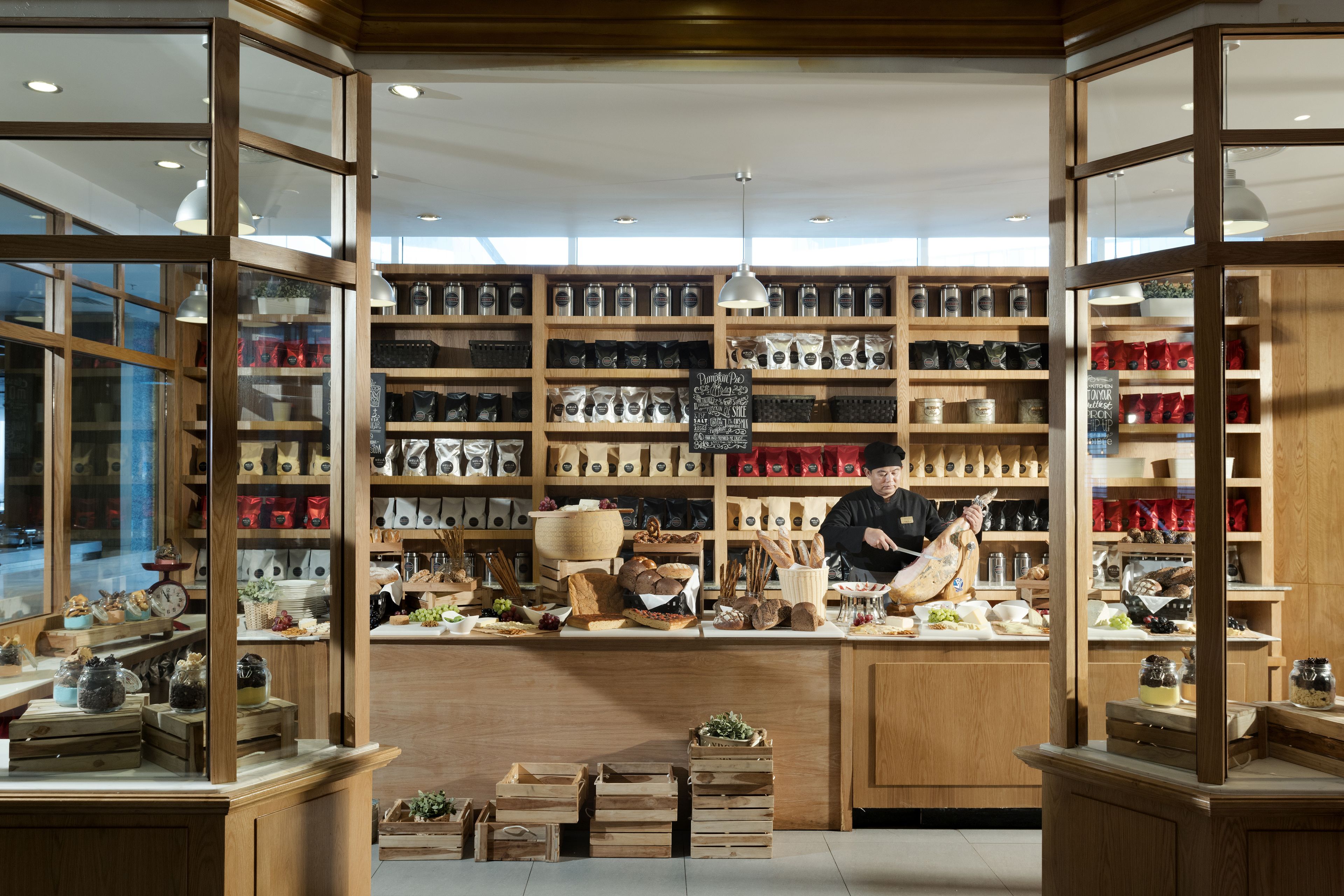 A bakery with wooden shelves stocked with various baked goods and a counter with bread and pastries.