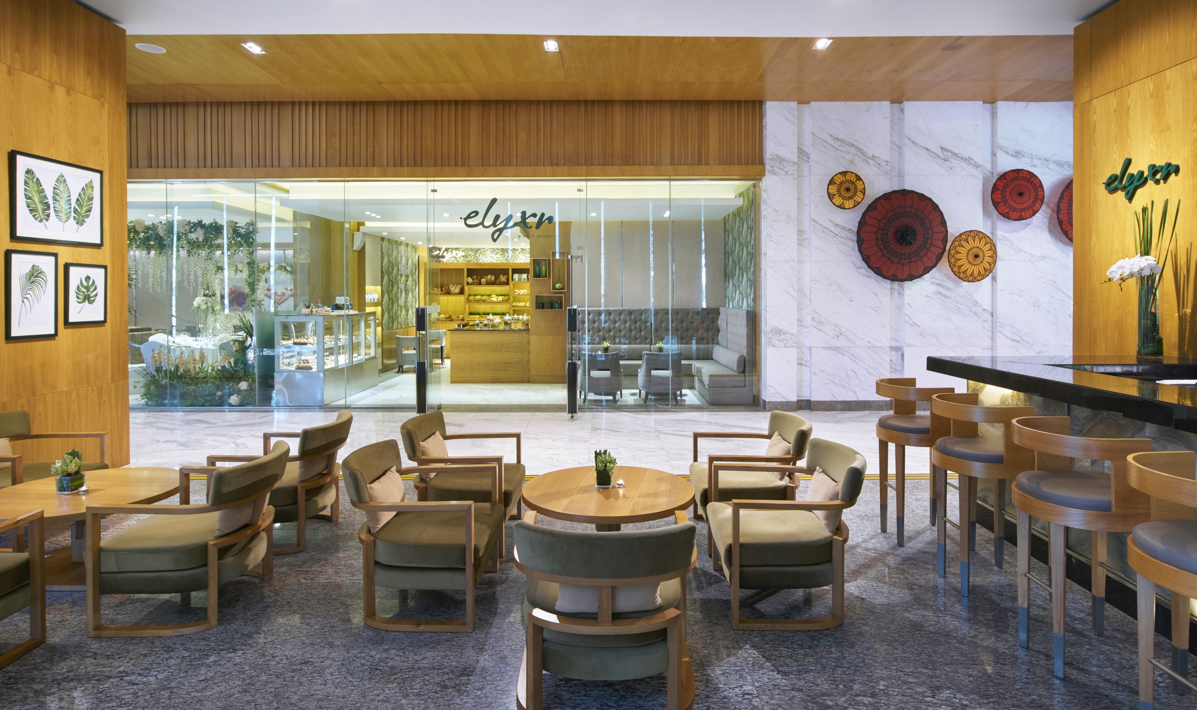 A modern interior with wooden paneling, a glass storefront, and a seating area with round tables and chairs.