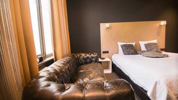 A modern bedroom with a large bed, a leather sofa, and a nightstand.