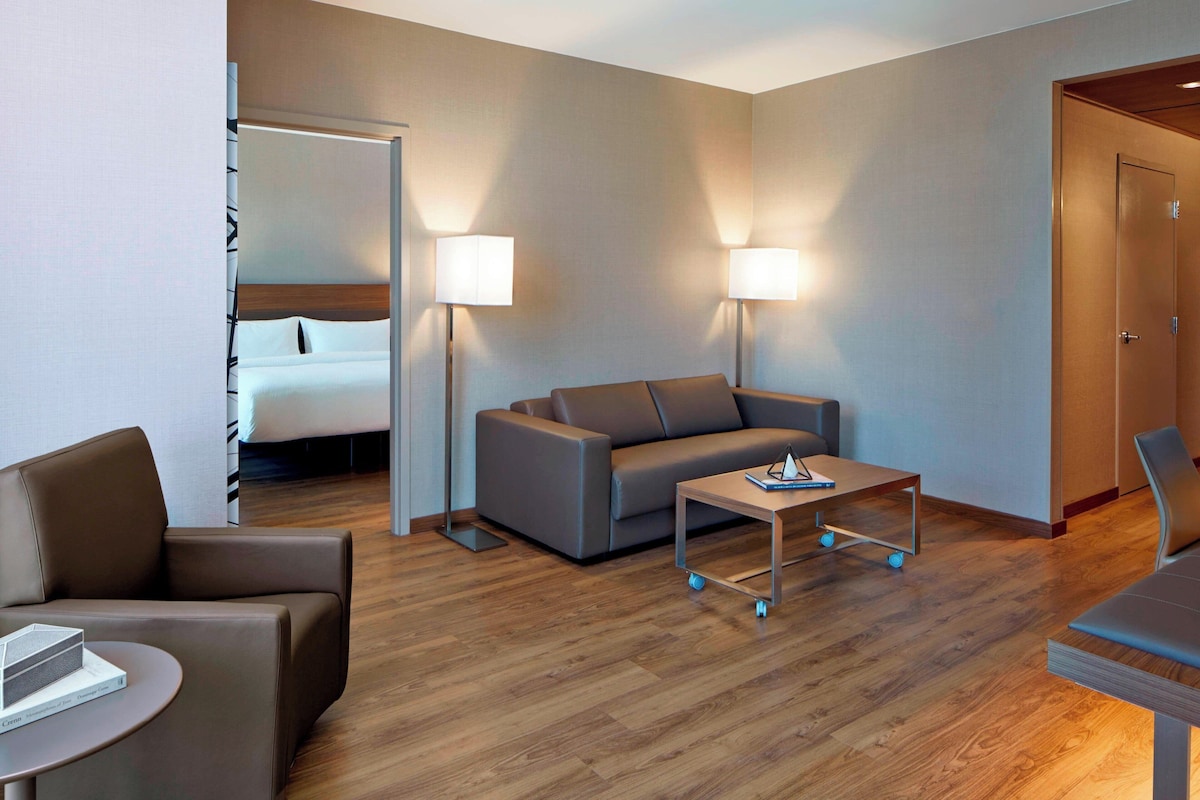 Une chambre d’hôtel moderne équipée d’un lit, d’un canapé, d’une petite table et de deux lampes.