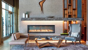 Een moderne woonkamer met een open haard, een bank, een salontafel en een fauteuil.