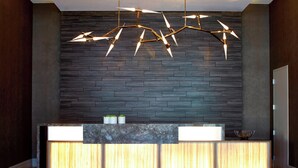 Uma receção com design moderno, uma parede de madeira escura e um candeeiro único.