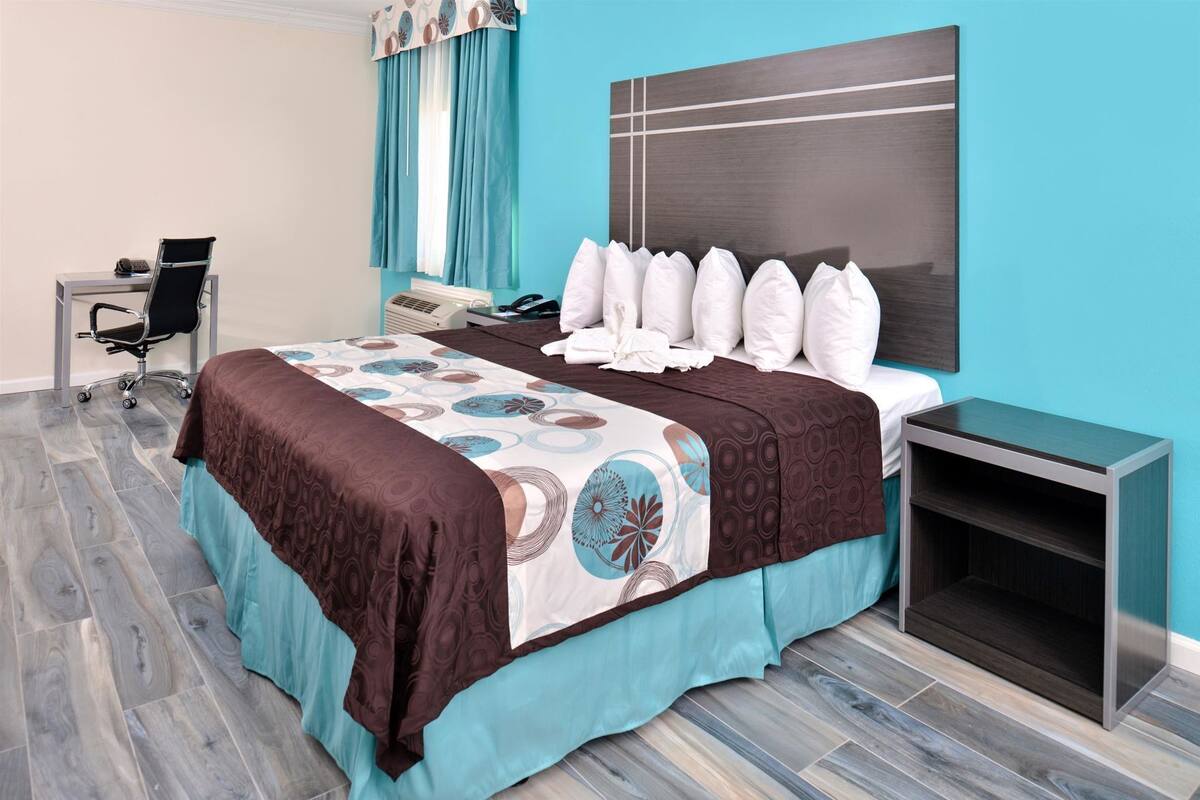 Une chambre d’hôtel avec un lit, un bureau, une chaise et une table de chevet.
