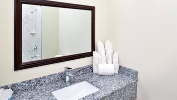 A bathroom with a marble sink, a large mirror, and a towel rack with folded towels.