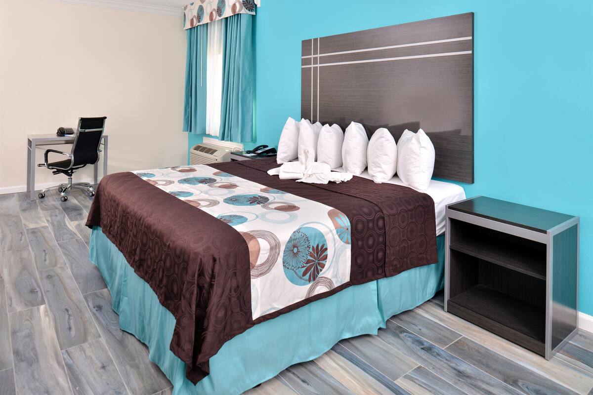Une chambre d’hôtel avec un lit, un bureau, une chaise et une table de chevet.