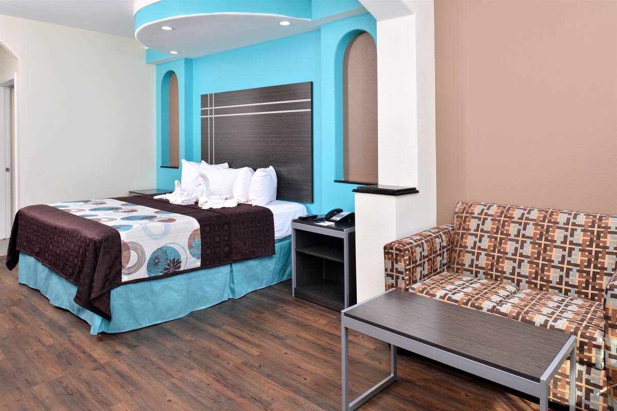 Une chambre d’hôtel avec un lit, une table de chevet, une chaise et une petite table.