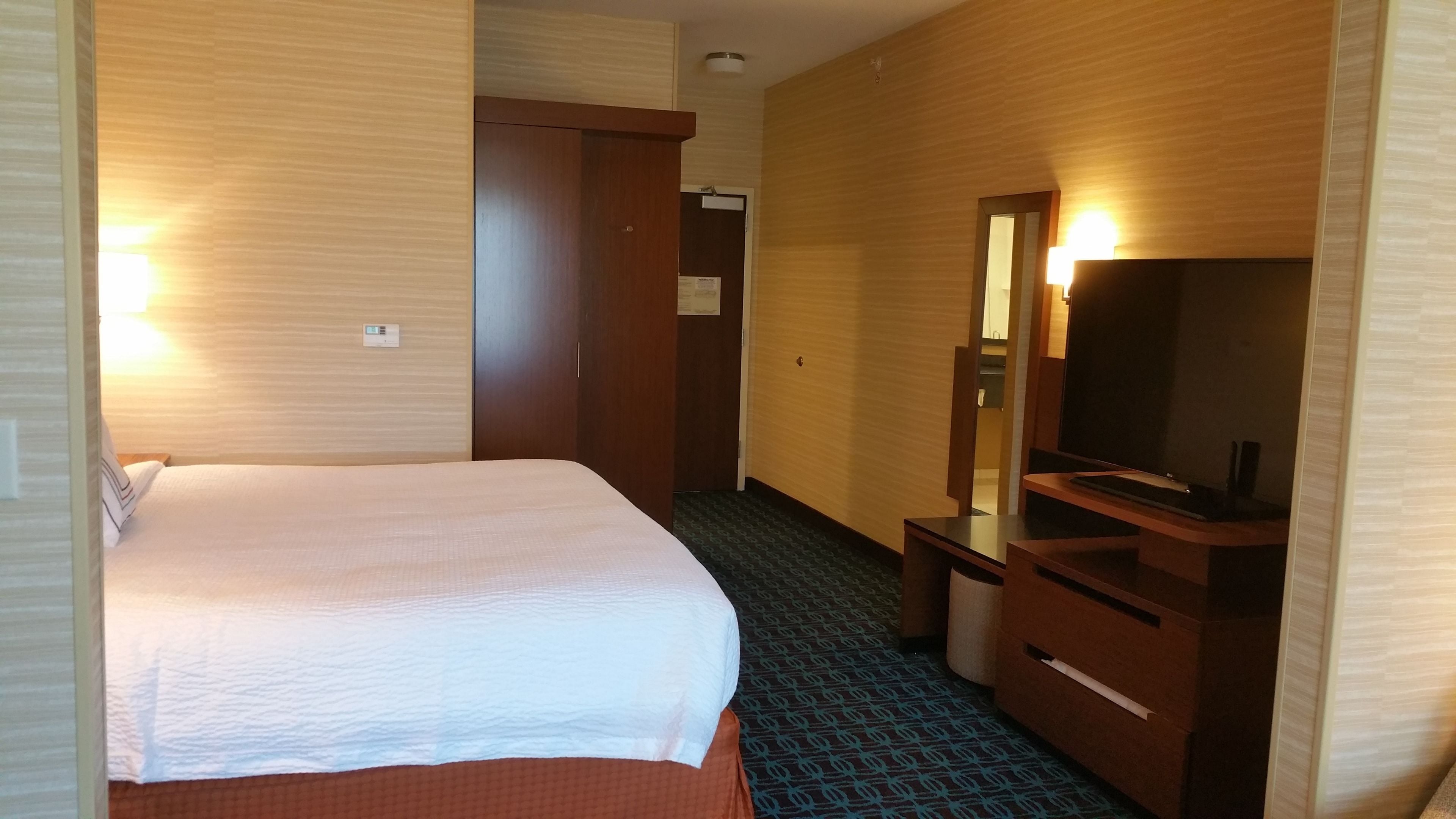 Ein Hotelzimmer mit Bett, Kommode, Spiegel und Fernseher.