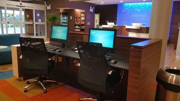 A hotel reception area with multiple computer workstations, a reception desk, and a corner market.