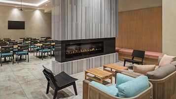 A modern lounge area with a fireplace, seating arrangements, and a ceiling fan.