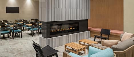 Un salon moderne doté d’une cheminée, de différents espaces de détente et d’un ventilateur de plafond.