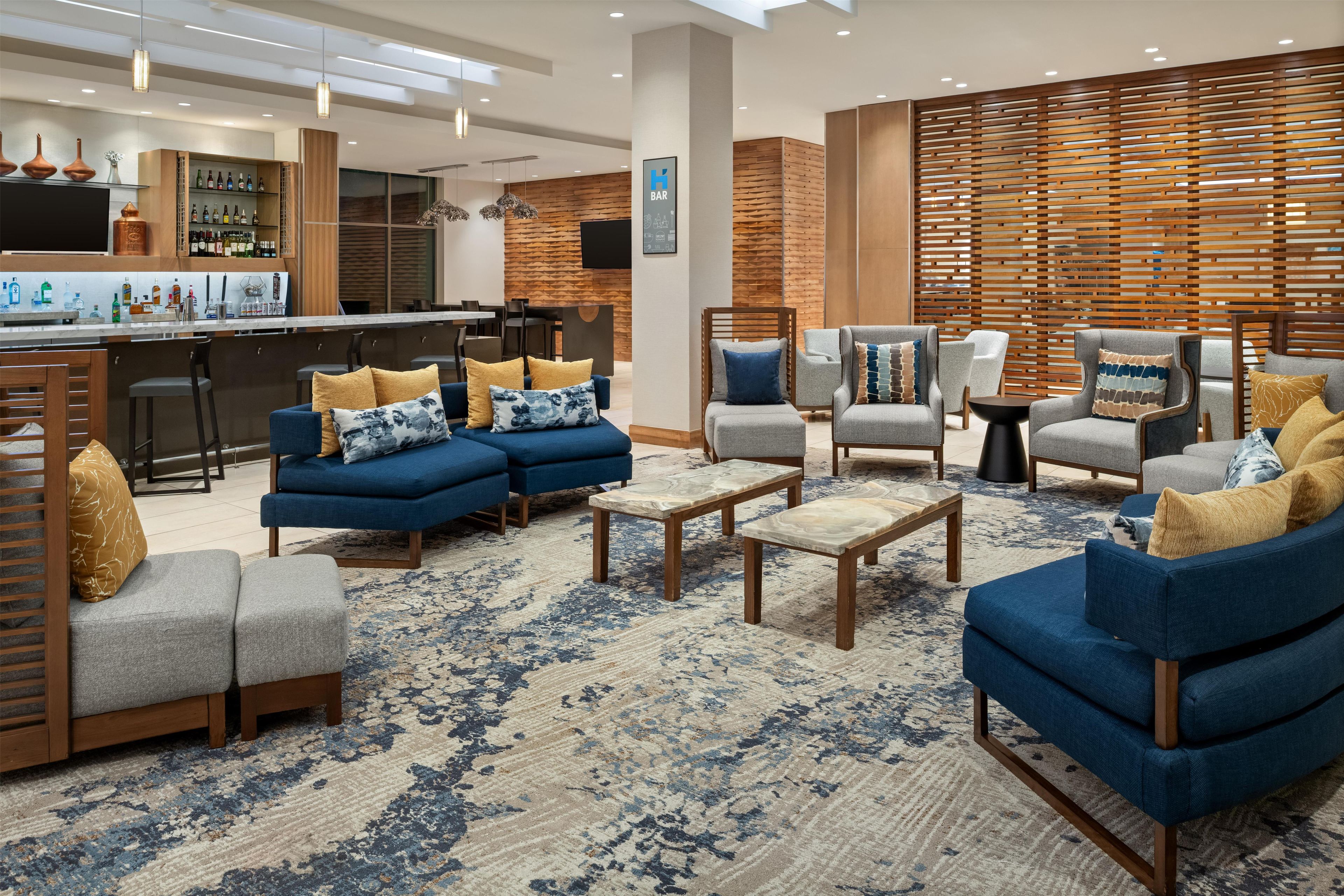 A modern lounge area with sofas, armchairs, and a bar.