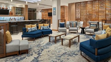 A modern lounge area with sofas, armchairs, and a bar.