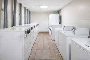 A laundry facility with rows of washing machines and dryers, a tiled floor, and a plain white wall. - Hyatt House at Anaheim Resort/Convention Center (Anaheim)