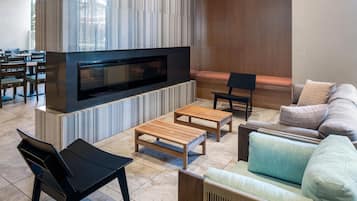 A modern living room with a flat-screen TV, wooden furniture, and a sofa with cushions.