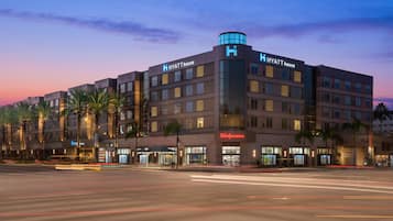 A multi-story hotel with a prominent 'Hyatt House' sign, a Walgreens store, and palm trees in front.