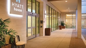 A modern hotel entrance with a sign reading "HYATT house," large glass doors, potted plants, and a tiled floor. - Hyatt House at Anaheim Resort/Convention Center (Anaheim)