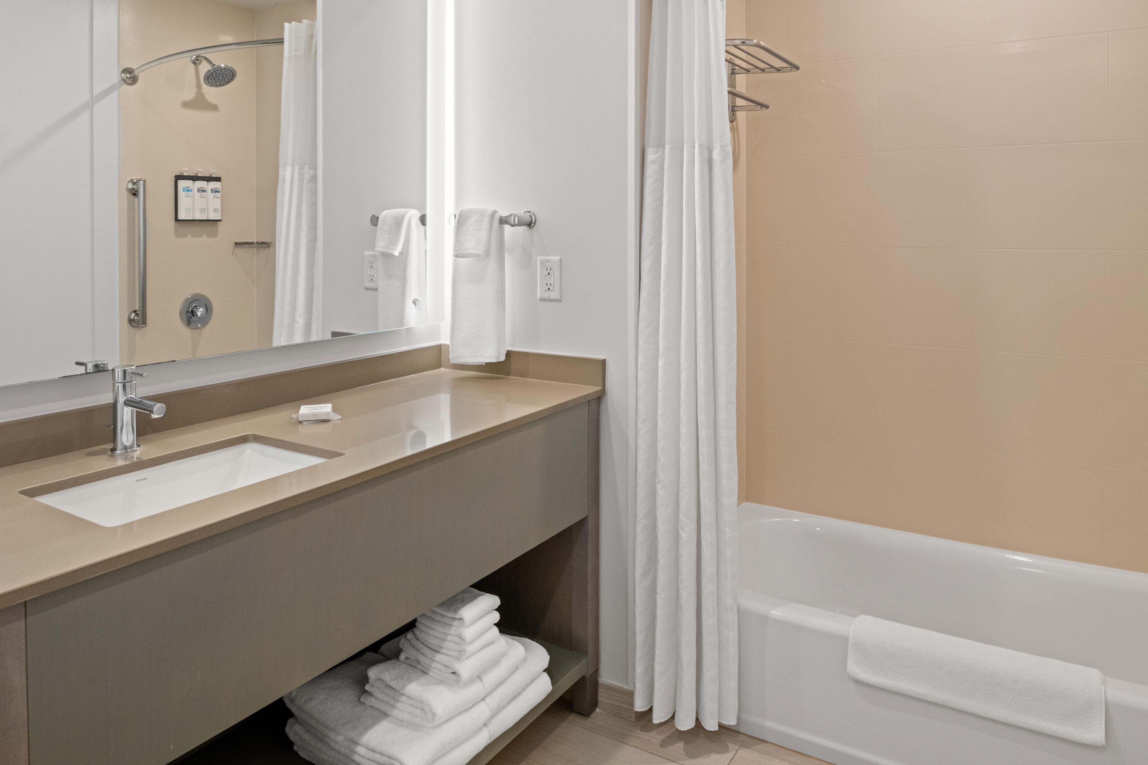 A bathroom with a sink, mirror, towel rack, and a bathtub.