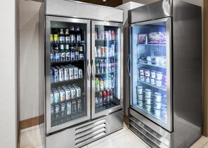 Un equipo de refrigeración comercial con varias estanterías llenas de bebidas y aperitivos.