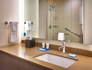 Un baño de hotel con lavamanos, espejo y ducha.