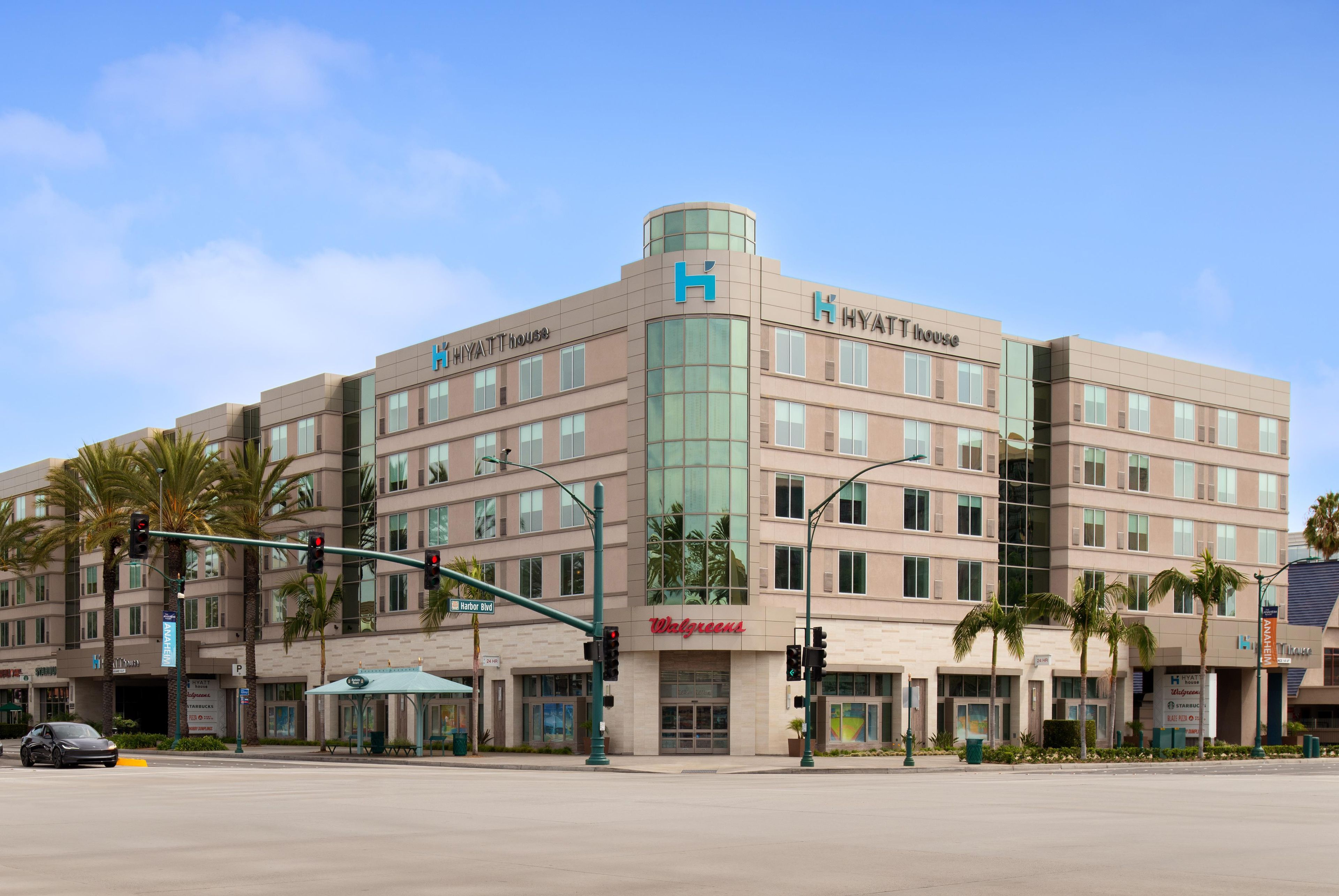 A multi-story hotel with a prominent 'Hyatt House' sign, a street-level Walgreens store, and a traffic light at an intersection.