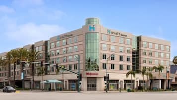A multi-story hotel with a prominent 'Hyatt House' sign, a street-level Walgreens store, and a traffic light at an intersection.