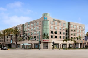 Un hotel de varios pisos con un cartel llamativo de 'Hyatt House', una tienda Walgreens a nivel de calle y un semáforo en una intersección.