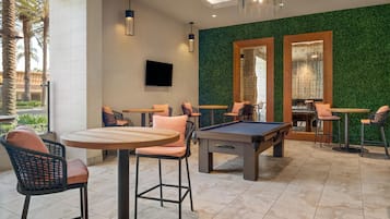 A pool table in a room with green walls, multiple seating areas, and a television mounted on the wall.