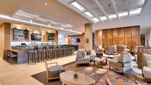 A modern hotel lobby with a bar area, seating arrangements, and a large screen. - Hyatt House at Anaheim Resort/Convention Center (Anaheim)