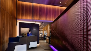 A modern reception area with wooden paneling, a reception desk, and a digital display wall. - LUMA Hotel Times Square (New York)