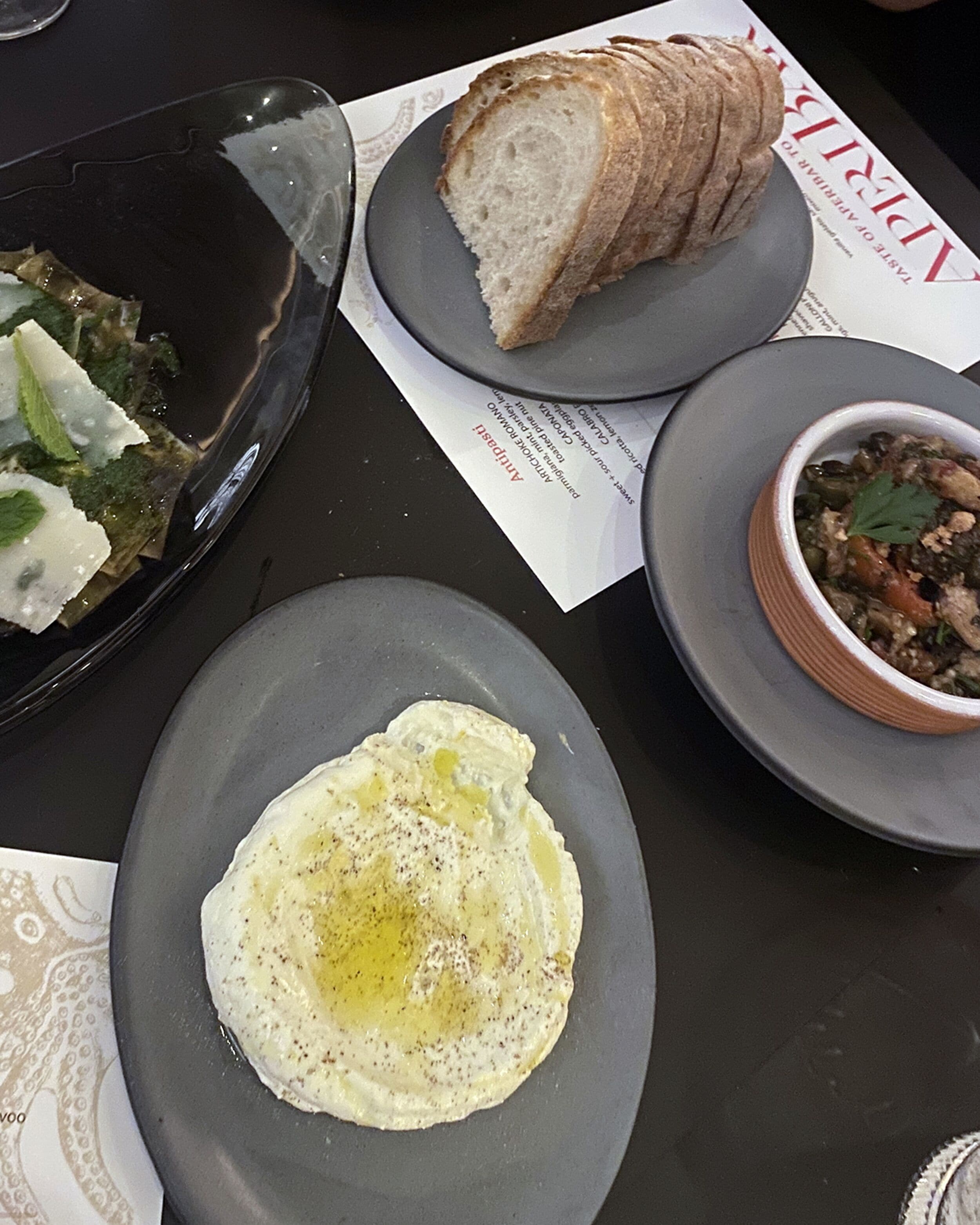 A table with a plate of bread, a bowl of soup, and a plate with an egg.